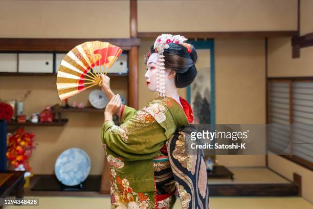 maiko (geisha in training) dancing with 'sensu' folding fan in japanese tatami room - geisha japan stock pictures, royalty-free photos & images