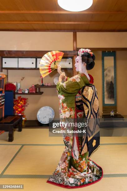full length portrait of maiko (geisha in training) dancing with 'sensu' folding fan in japanese tatami room - geisha in training stock pictures, royalty-free photos & images