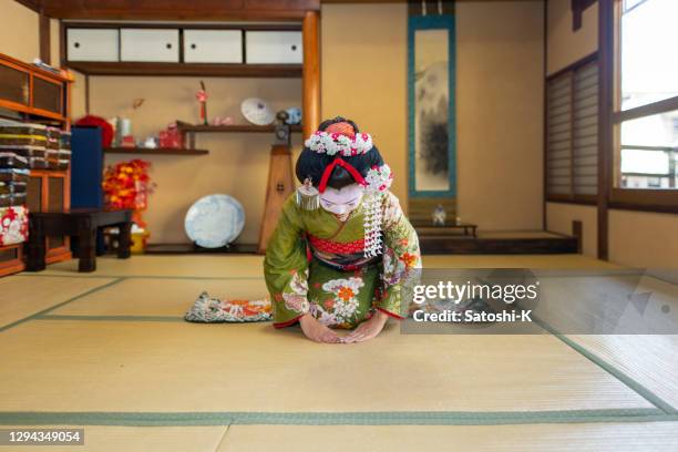 maiko (geisha à l’entraînement) assis sur des talons et profondément s’inclinant dans la salle tatami japonaise - kimono photos et images de collection