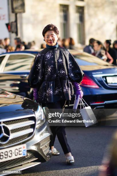 Guest wears glasses, a black jacket with rhinestones embroideries, black pants, glittering silver moccasins, outside Dior, during Paris Fashion Week...