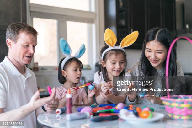 gelukkige familie die paaseieren schildert - easter bunny man stockfoto's en -beelden