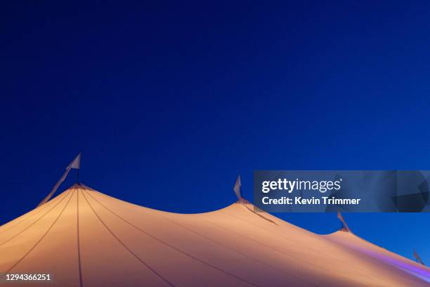 top of large event tent lit up during dusk - zirkuszelt stock-fotos und bilder