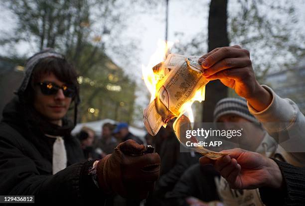Protesters burn fake bills as they still camp in front of the Beursplein 5 stock exchange building in Amsterdam on October 17 as part of Europe-wide...