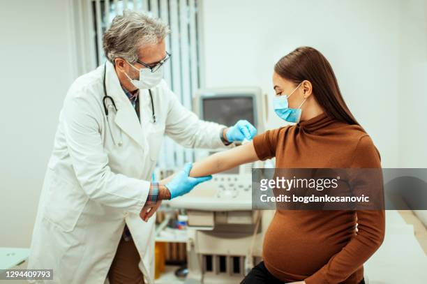 arts die een injectie geeft aan zwangere vrouw - foetus stockfoto's en -beelden