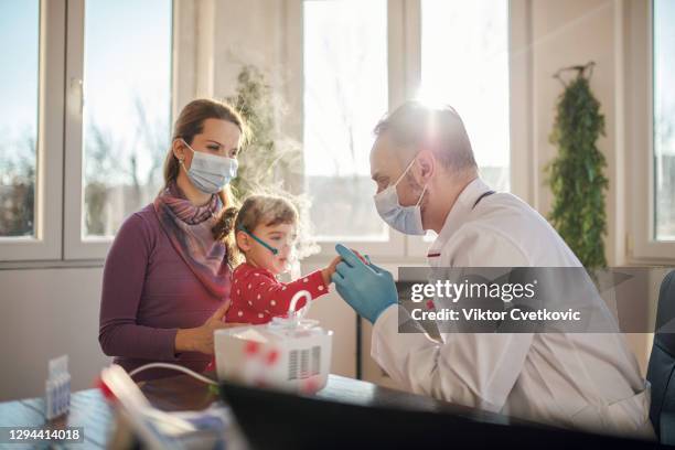 médico que aplica tratamiento de inhalación de medicamentos en una niña pequeña - nebulizador fotografías e imágenes de stock