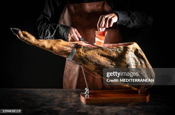 iberian ham serrano ham cutting slice male hands and knife on dark moody - serrano ham stock pictures, royalty-free photos & images