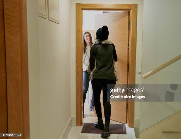 smiling young woman opening the door of her house to her friend. friendship concept - guest door ストックフォトと画像
