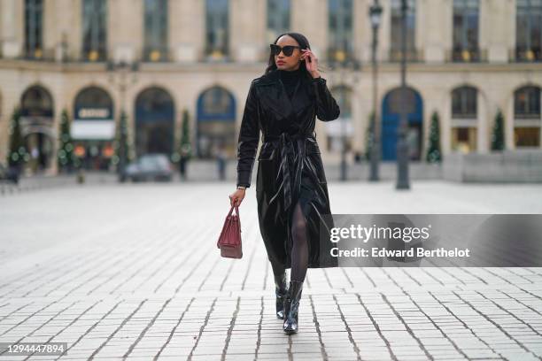 Emilie Joseph wears sunglasses from Gentle Monster, a black turtleneck pullover from Uniqlo, a black shiny liquid vinyl trench coat from Topshop, a...