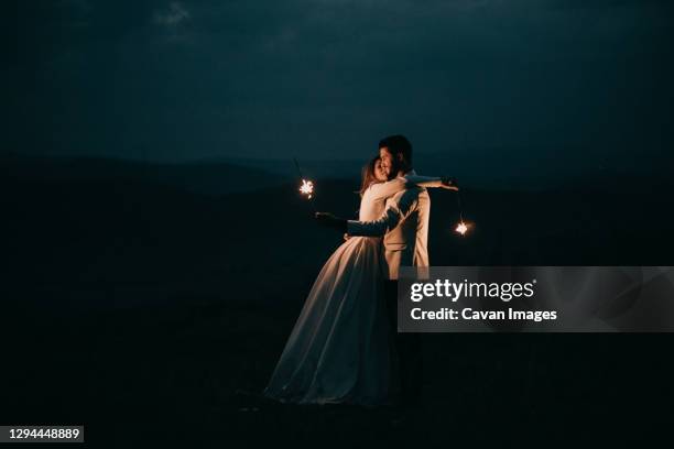 young couple playing with fireworks at night after the wedding - wedding elegant ストックフォトと画像