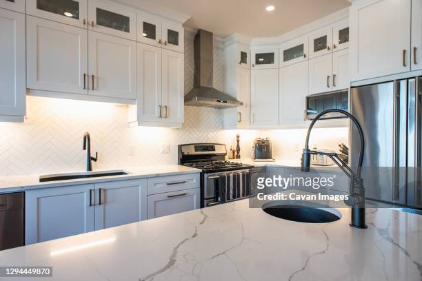 modern kitchen with white cupboards, dark island and gold accents. - quartz stockfoto's en -beelden