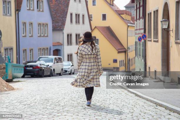 a woman wearing a long coat walking the streets of a medieval town. - 石畳　道 ストックフォトと画像
