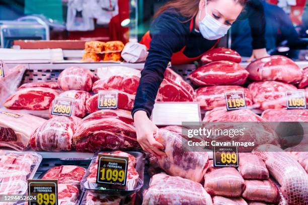 butcher woman choosing meat from the counter - metzgerin stock-fotos und bilder