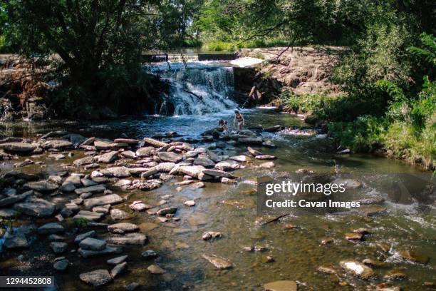 pull back of two children playing in a stream near waterfall - denver summer stock pictures, royalty-free photos & images