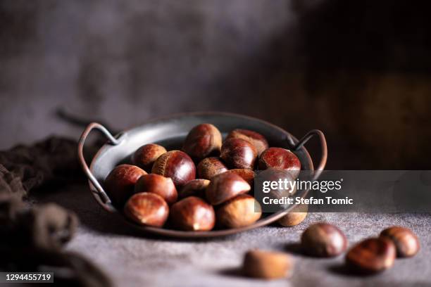 chestnuts on a artistic metal plate in a rustic dark setup - chestnut stock pictures, royalty-free photos & images