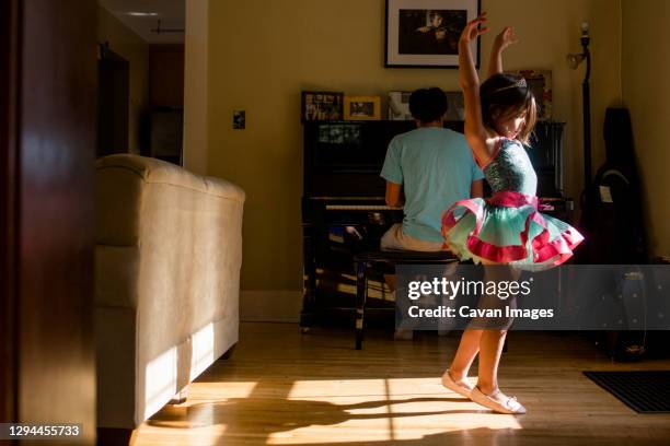 a little girl in tutu raises her arm to dance to father's piano music - kids tiara stock pictures, royalty-free photos & images