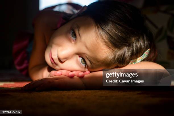 close-up of small child laying on the floor in a patch of bright light - eye patch stockfoto's en -beelden