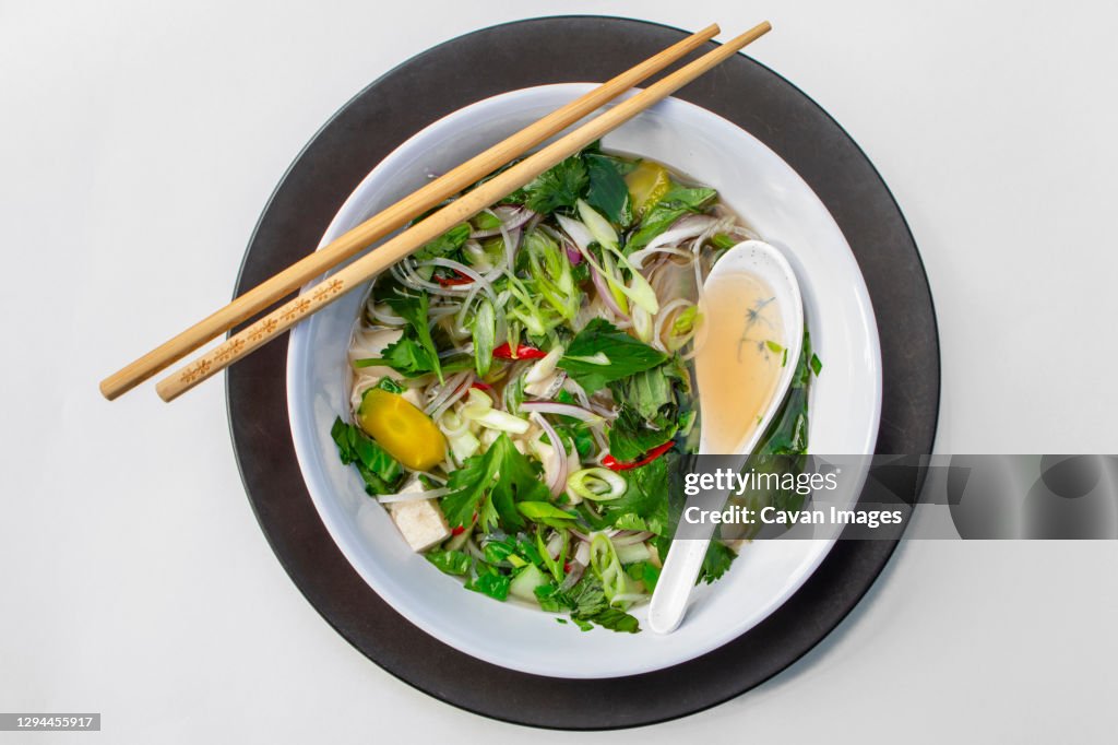 Above-view of bowl of asian noodle soup with chopsticks and spoon