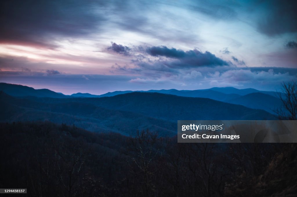 Dramatic pink and purple clouds over smokey mountains at sunrise