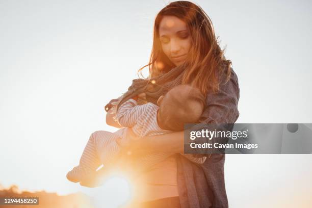 mom smiling breastfeeding baby outdoors during sunset - golden hour woman stock pictures, royalty-free photos & images