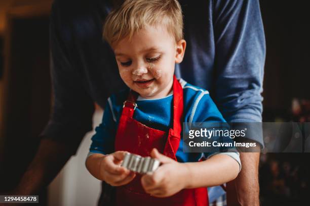 adorable boy baking christmas cookies with face full of flour - flour christmas stock pictures, royalty-free photos & images