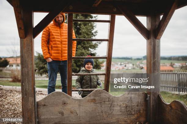 dad and son at playground in winter climbing ladder to wooden house - baby winter farm son stock pictures, royalty-free photos & images