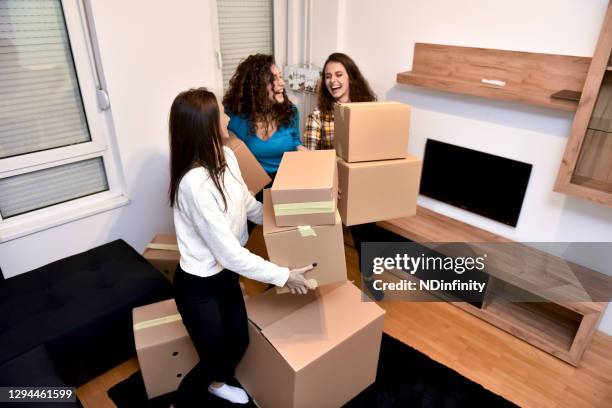 young girl is helped by her friends to move to a new home stock photo - college apartment stock pictures, royalty-free photos & images