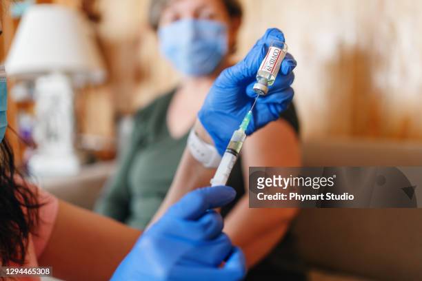 doctor giving covid vaccine to senior woman - covid 19 vaccine stock pictures, royalty-free photos & images
