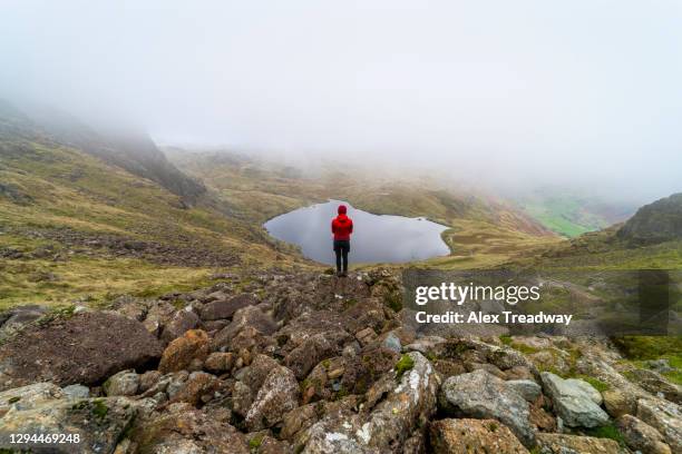 a woman stands infront of stickle tarn on cloud covered day in the lake district - english lake district stock pictures, royalty-free photos & images