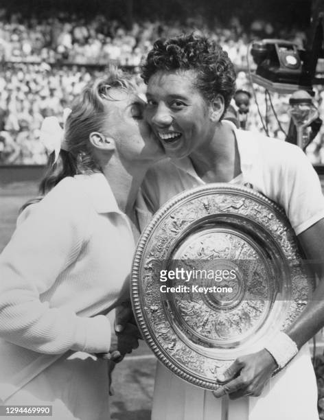 Althea Gibson of the United States holds the Rosewater Plate and is congratulated with a kiss by compatriot Darlene Hard after their Women's Singles...
