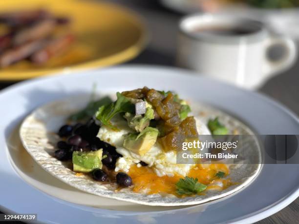 huevos rancheros egg breakfast on tortilla with avocado and black beans - huevos-rancheros fotografías e imágenes de stock