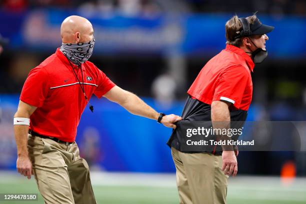 Director of strength and conditioning Scott Sinclair pulls head coach Kirby Smart of the Georgia Bulldogs back to the sidelines during the first half...