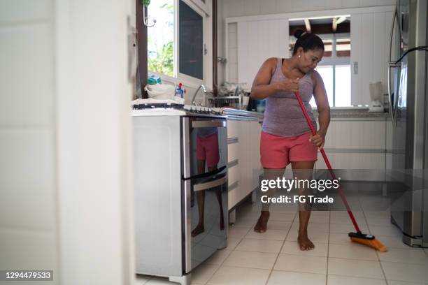 mujer madura barriendo piso de cocina - barrer fotografías e imágenes de stock