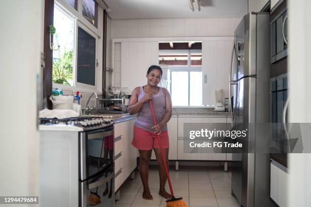 portrait of a mature woman sweeping kitchen - homemaker stock pictures, royalty-free photos & images