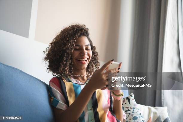 adolescente usando smartphone no sofá - aplicação móvel - fotografias e filmes do acervo