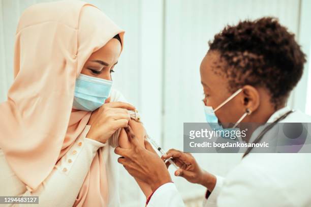 muslim patient is taking a vaccine from a doctor - religion stock pictures, royalty-free photos & images