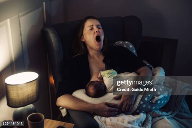 tired mother yawning while doing breastfeeding at home at night. - mother sleeping baby bildbanksfoton och bilder