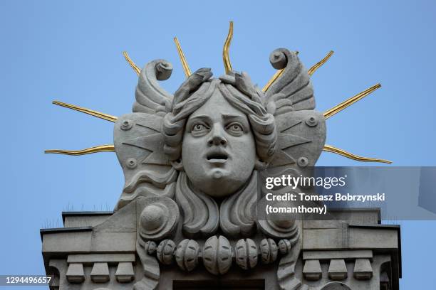 apollo head with a radiant sunny aureole at the top of the palace of fine arts in krakow - roman god stock pictures, royalty-free photos & images