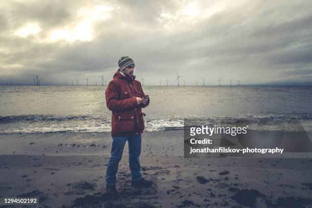 male looking thoughtful on smartphone screen - windmill denmark stock pictures, royalty-free photos & images
