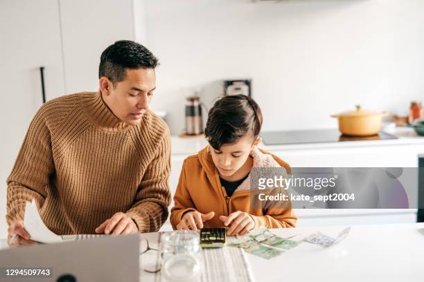 family finances and math lessons during homeschooling time.dad and son with cash  sitting in the kitchen - child saving stock pictures, royalty-free photos & images
