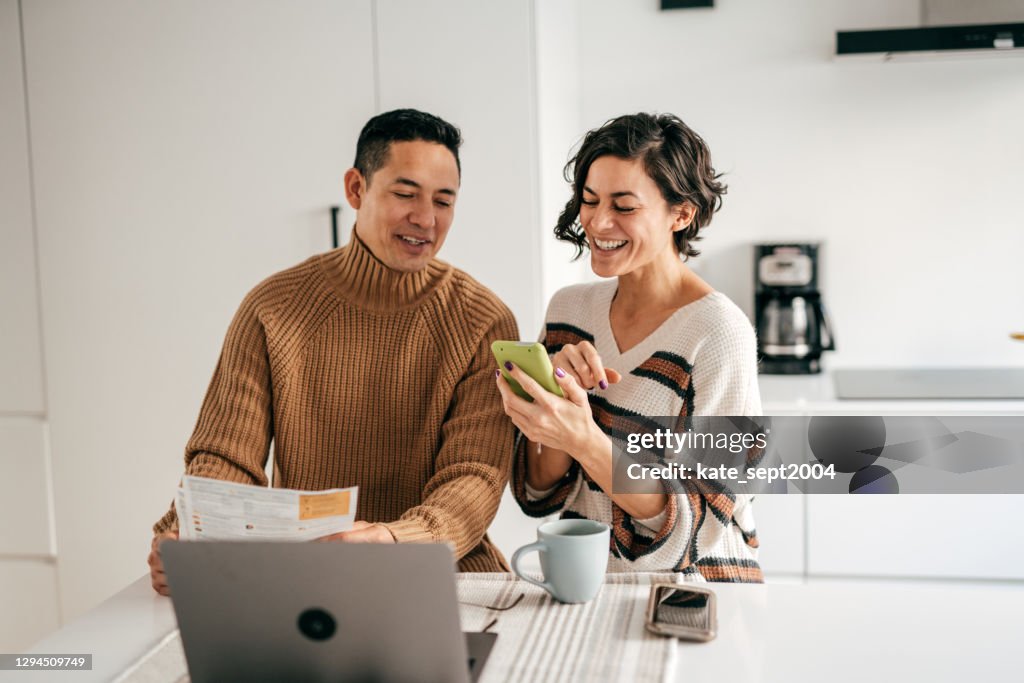 Online banking for family budget - couple in the kitchen with bills