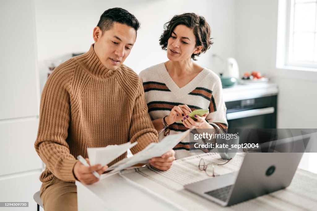 When Paying the Mortgage is a Struggle. Couple sitting in the kitchen with receipts and calculator