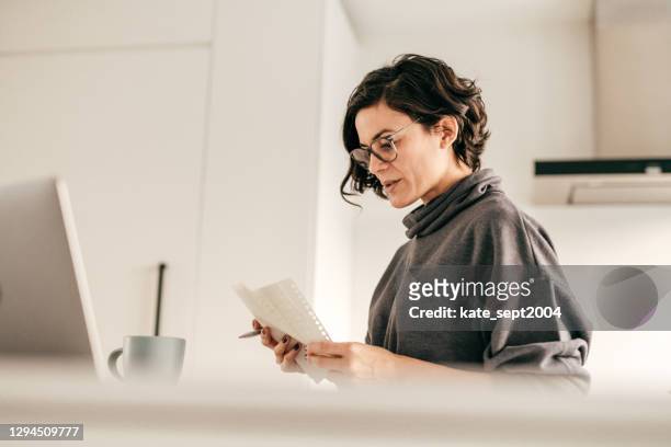 online bankieren en boekhouding vanuit het binnenlandse kantoor in de keuken - leanincollection working women stockfoto's en -beelden
