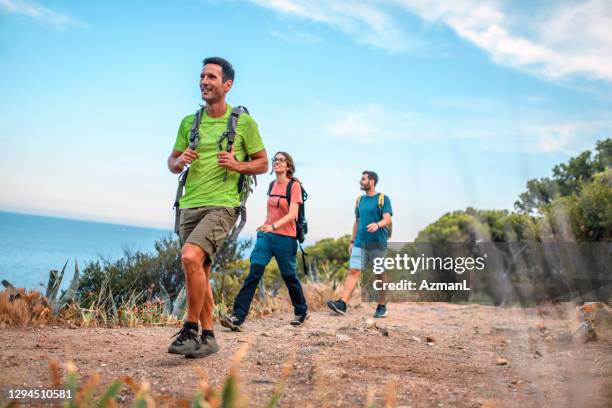 energetic spanish backpackers walking on coastal trail - approaching imagens e fotografias de stock