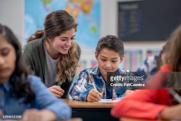 teacher helping student in elementary classroom - teacher stock pictures, royalty-free photos & images