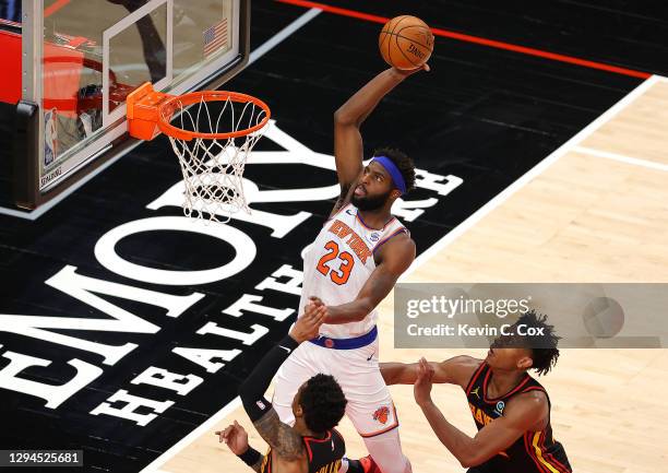 Mitchell Robinson of the New York Knicks dunks an alley-oop pass against John Collins and De'Andre Hunter of the Atlanta Hawks during the second half...