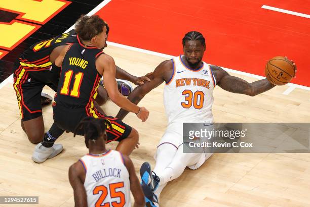 Julius Randle of the New York Knicks grabs a loose ball against Trae Young and Clint Capela of the Atlanta Hawks during the second half at State Farm...