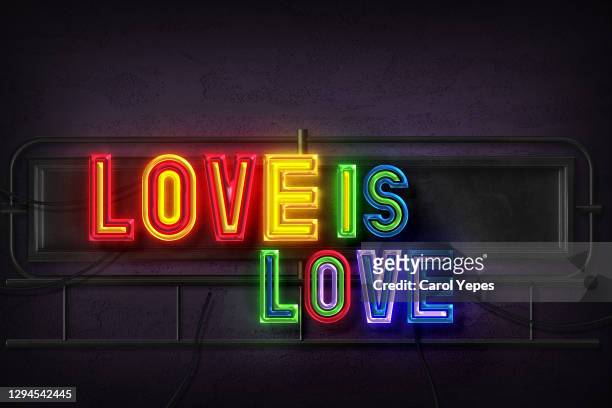 love is love text in rainbow neon style on wall - love is /// stock-fotos und bilder