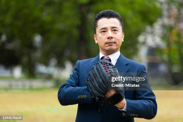 businessman standing with gloves in the park - baseball glove stock-fotos und bilder