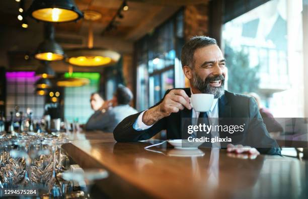 mature handsome man having morning coffee at a bar. - coffee moustache stock pictures, royalty-free photos & images