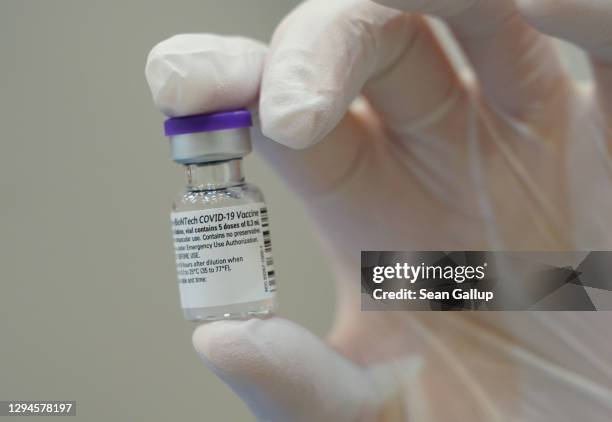 Doctor holds up a bottle of the Pfizer/BioNTech vaccine against Covid-19 at the vaccination center at the Metropolis-Halle events center on the first...